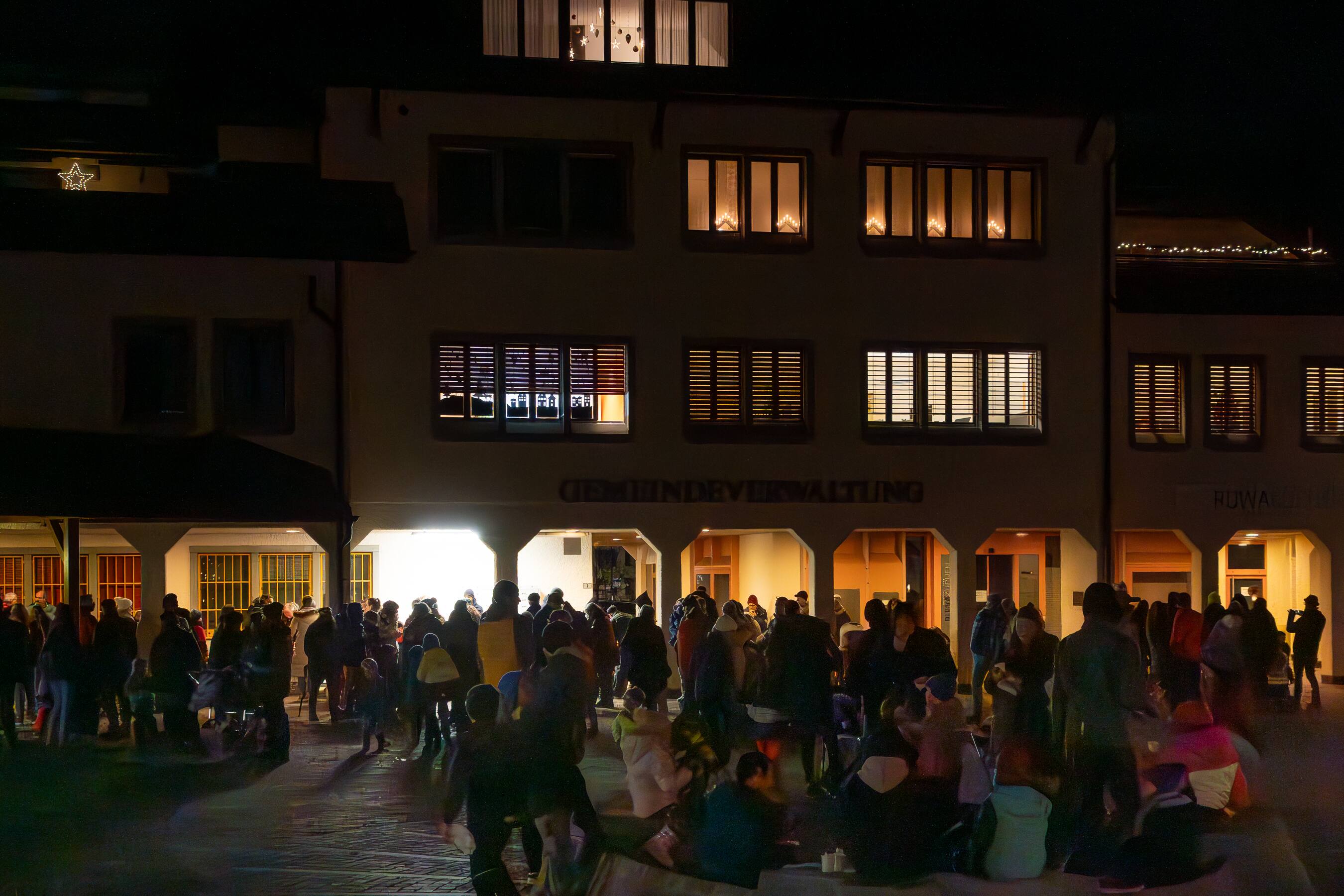 Publikum vor der beleuchteten Gemeindeverwaltung am Abend des Einzugs
