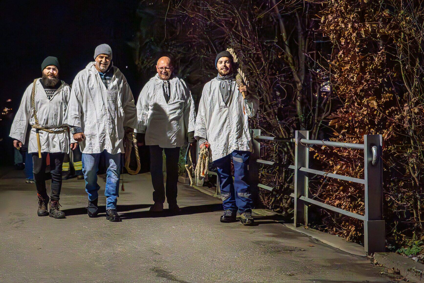 Vier Geisslechlöpfer in weissen Hemden auf dem Weg ins Dorf